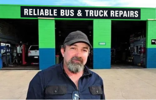 A Man With a Beard is Standing in Front of a Repair Shop — Reliable Bus and Truck Repairs In Caloundra West, QLD