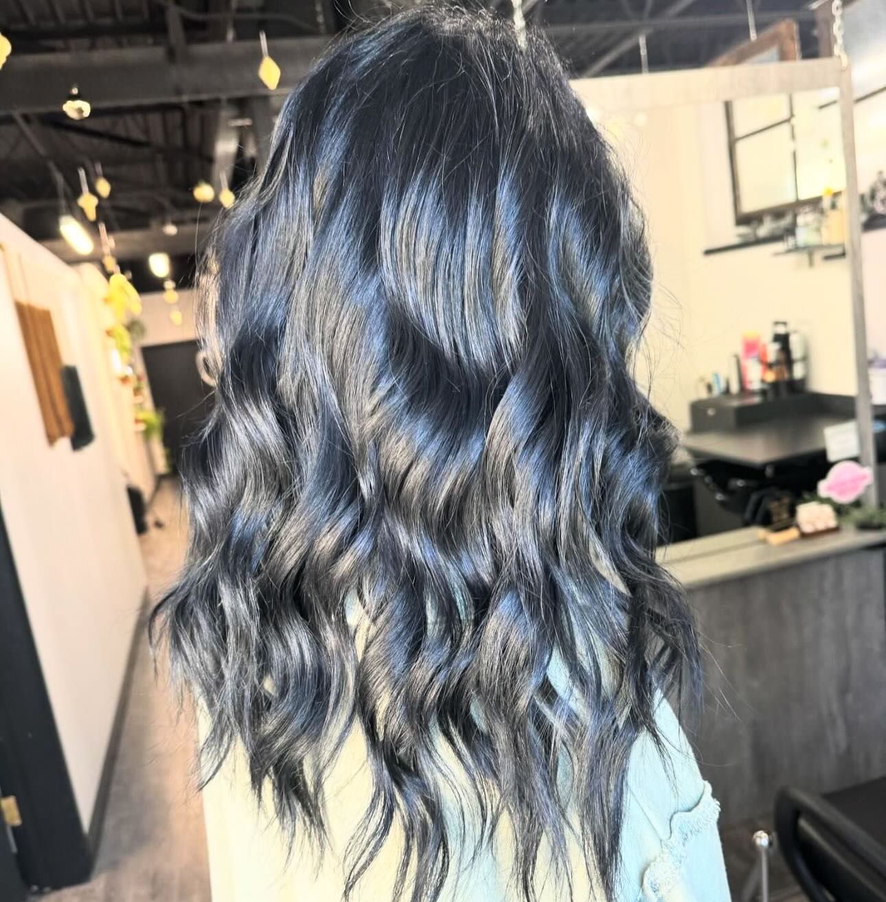 Dark wavy hair styled with soft, defined curls in a salon setting.