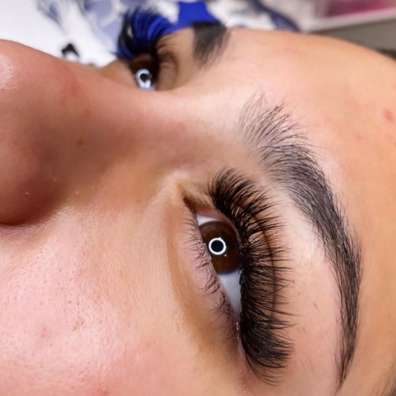 Close-up of a person with dark, dense, professionally applied eyelash extensions on one eye.