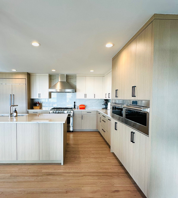 Bright modern kitchen with light wood cabinets, white countertops, island, and stainless steel appliances