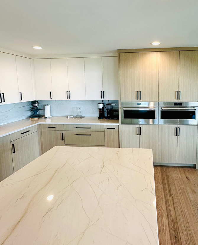 Modern bright kitchen with white cabinets, wood accents, and a large marble island