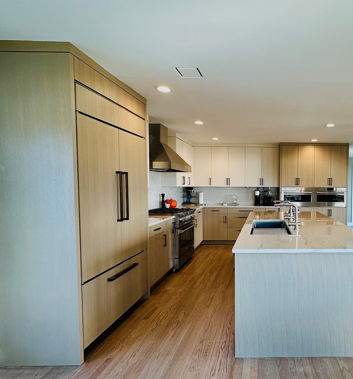 Modern open-plan kitchen with light wood cabinets, island, stainless appliances, and hardwood floor
