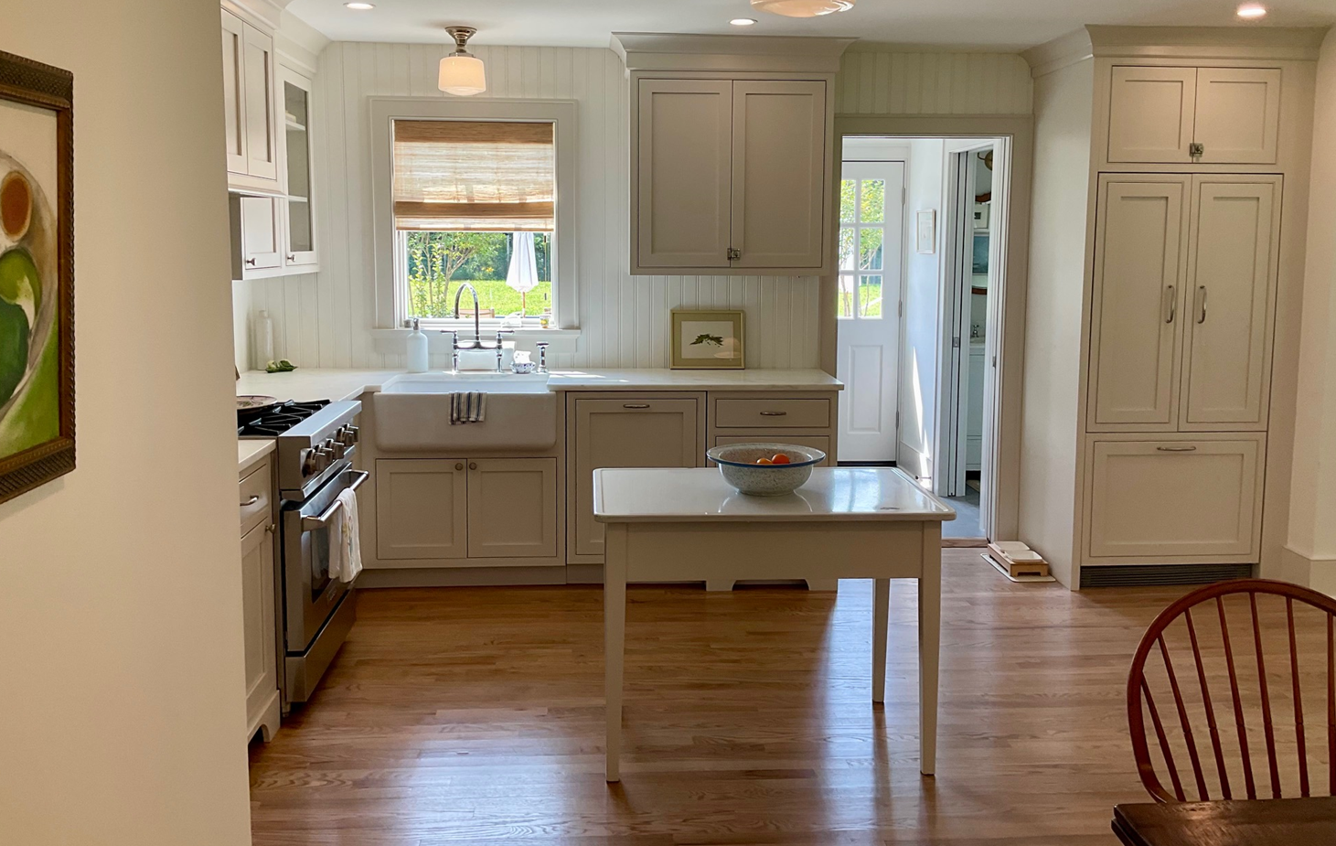 Bright kitchen with white cabinets, wood floor, central island, and window over the sink