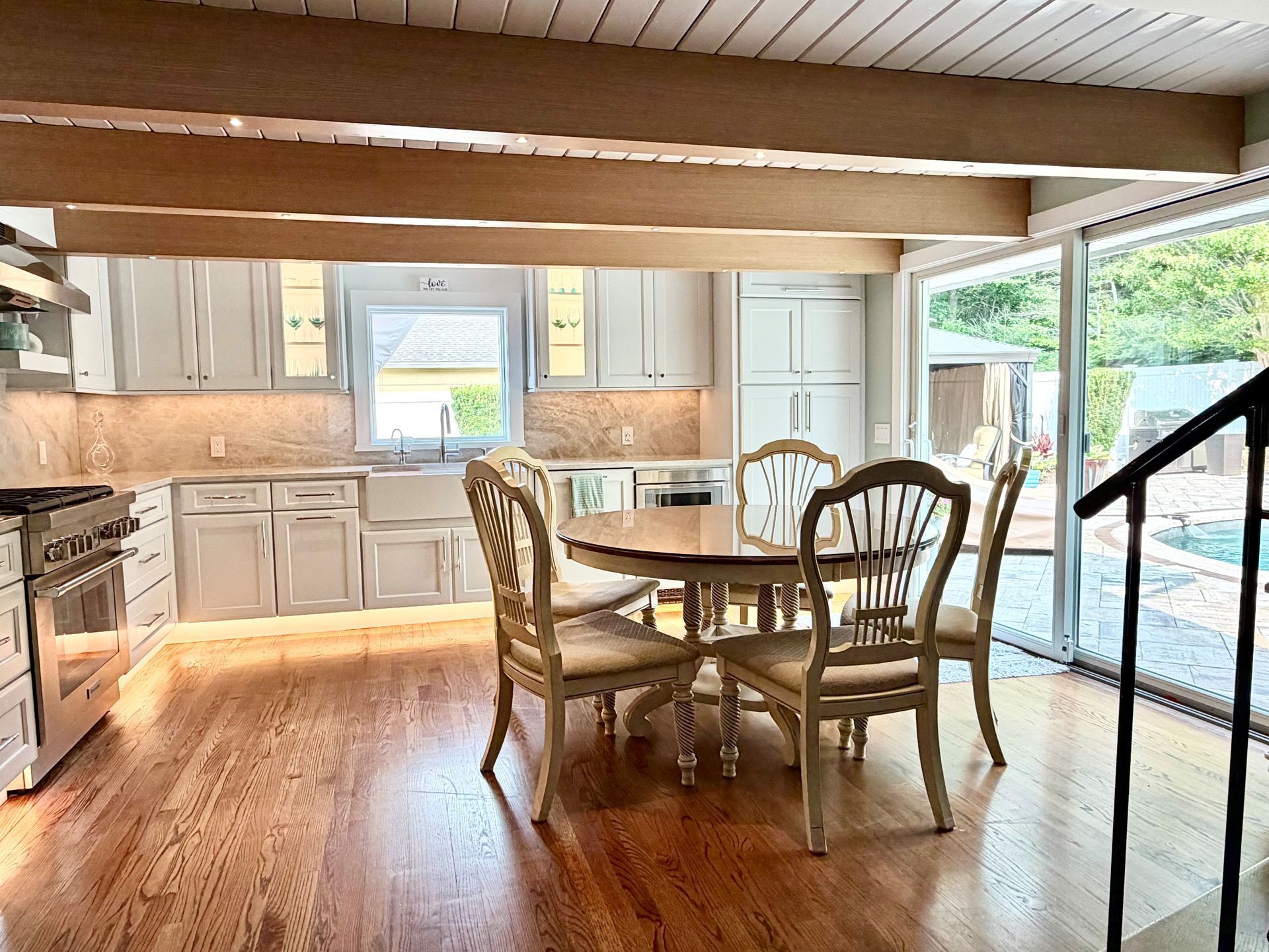 Bright kitchen with wooden table, light cabinets, and large sliding glass doors to a deck.