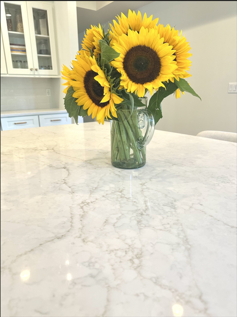 Sunflowers in a glass vase on a white marble kitchen island
