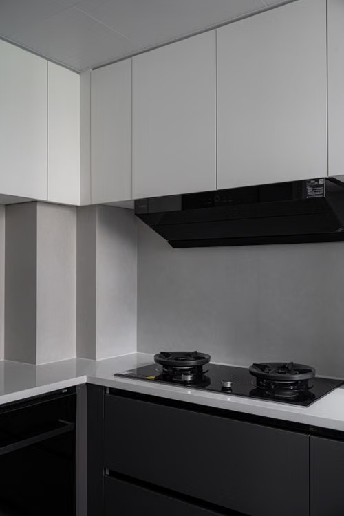 Modern kitchen corner with black cooktop, white cabinets, and black range hood