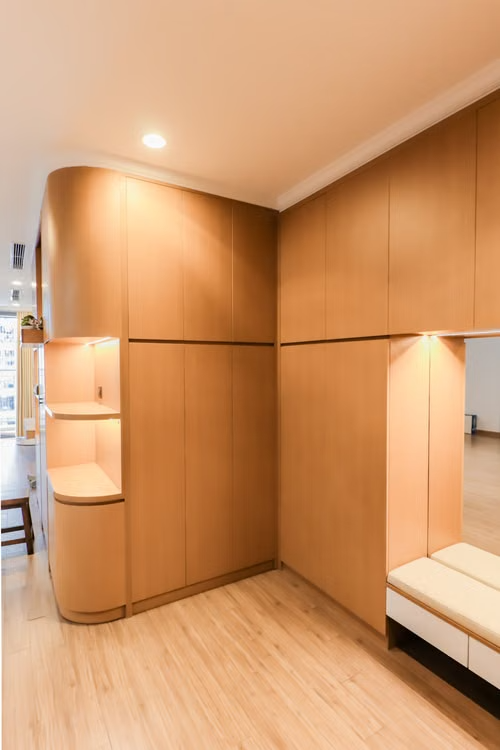 Wood-paneled hallway with built-in shelves, recessed lighting, and a bench near a doorway