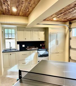 Empty walk-in closet with light wood shelves, hanging rods, drawers, and a white ottoman