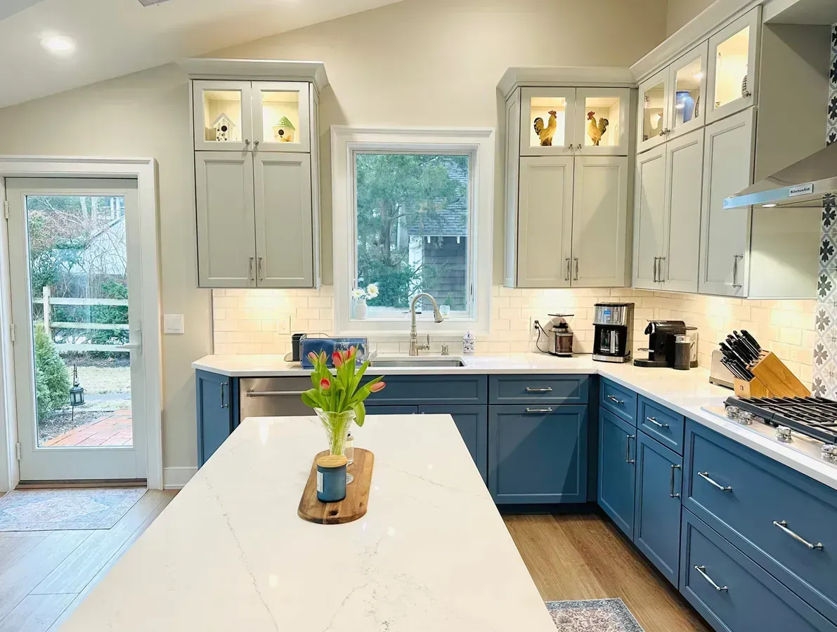Modern kitchen with wood cabinets, marble floor, and a built-in desk area under warm ceiling lights