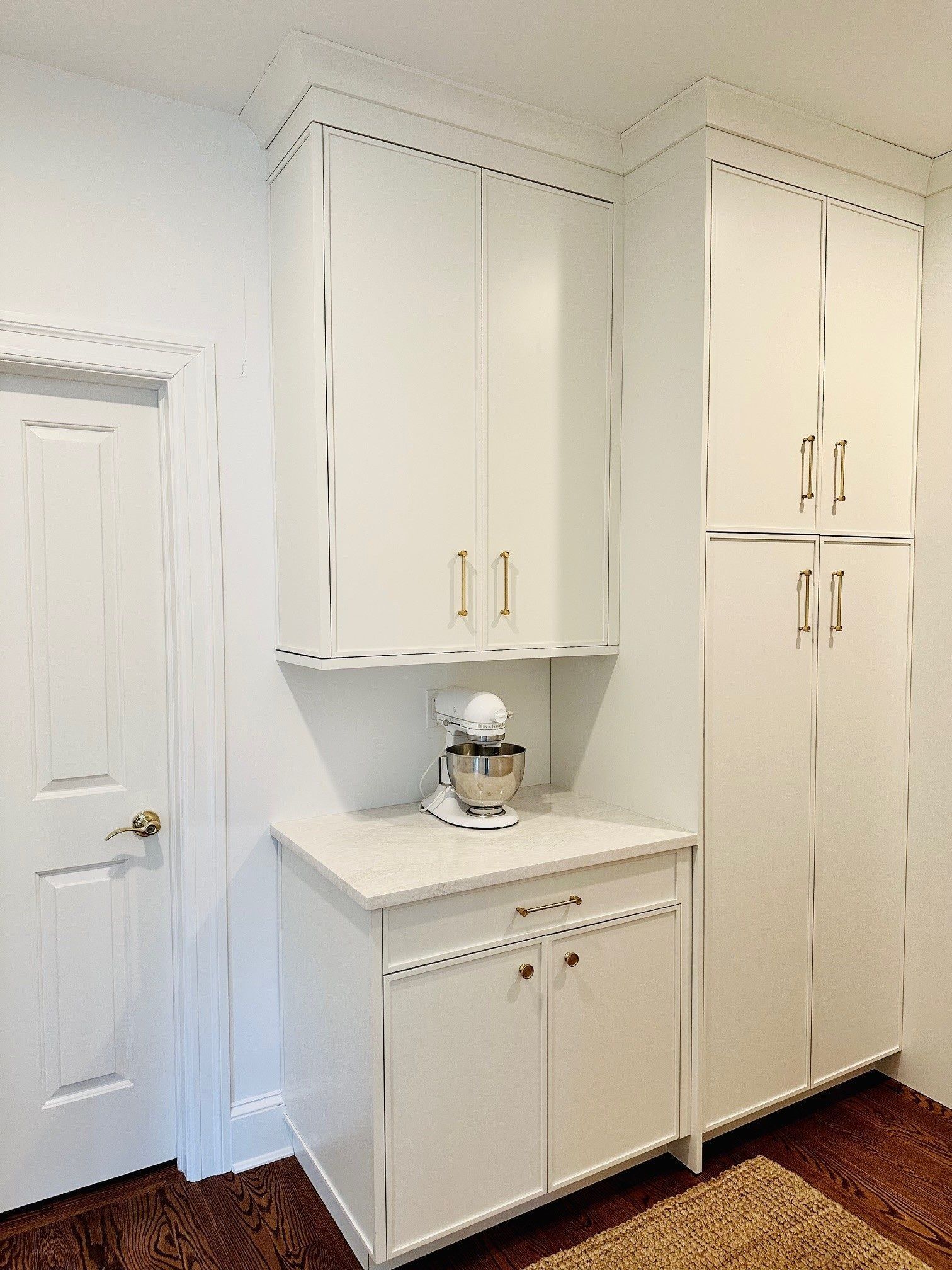 Bright white laundry room with built-in cabinets, a countertop, and stacked storage closets.