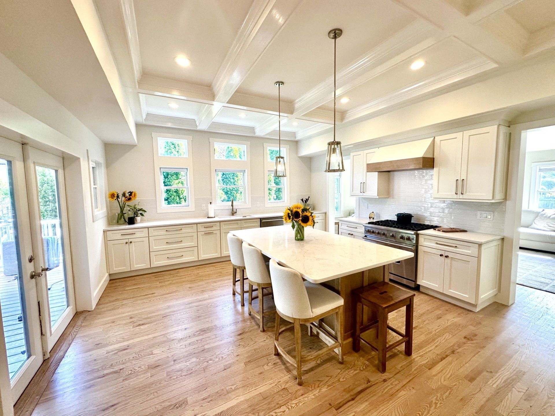 Bright, airy kitchen with white cabinets, large island, hardwood floors, and pendant lights