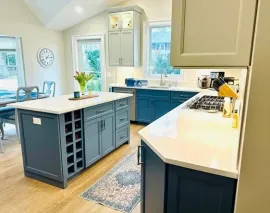 Bright kitchen with blue island, white countertops, and sunlight through windows