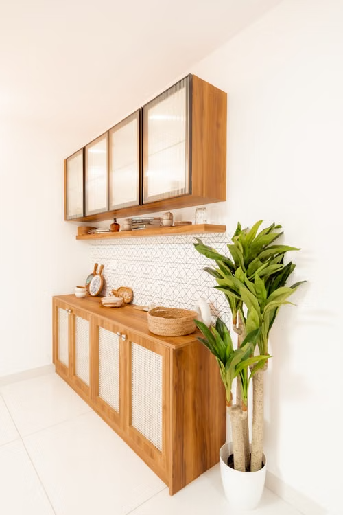 Modern kitchen with wooden cabinets, white tile backsplash, and a potted green plant on the counter