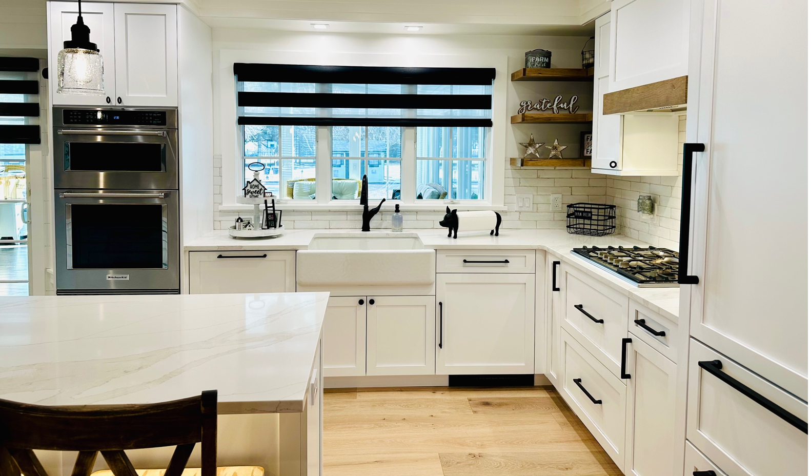 Bright white kitchen with island, stainless appliances, and a large window over the sink