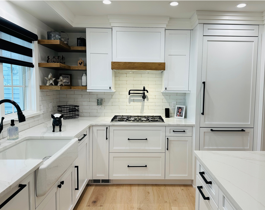 Bright white kitchen with farmhouse sink, gas range, and wooden floor, viewed from the doorway