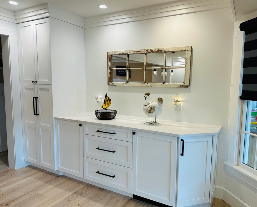 Bright white built-in cabinet with mirror, drawers, decor, and window in a modern room
