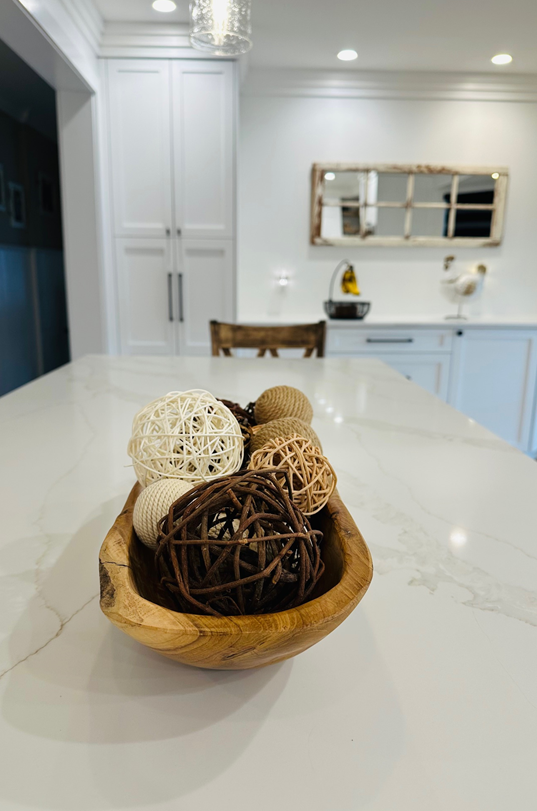 Decorative woven bowl with wicker balls on a white kitchen island in a bright modern kitchen