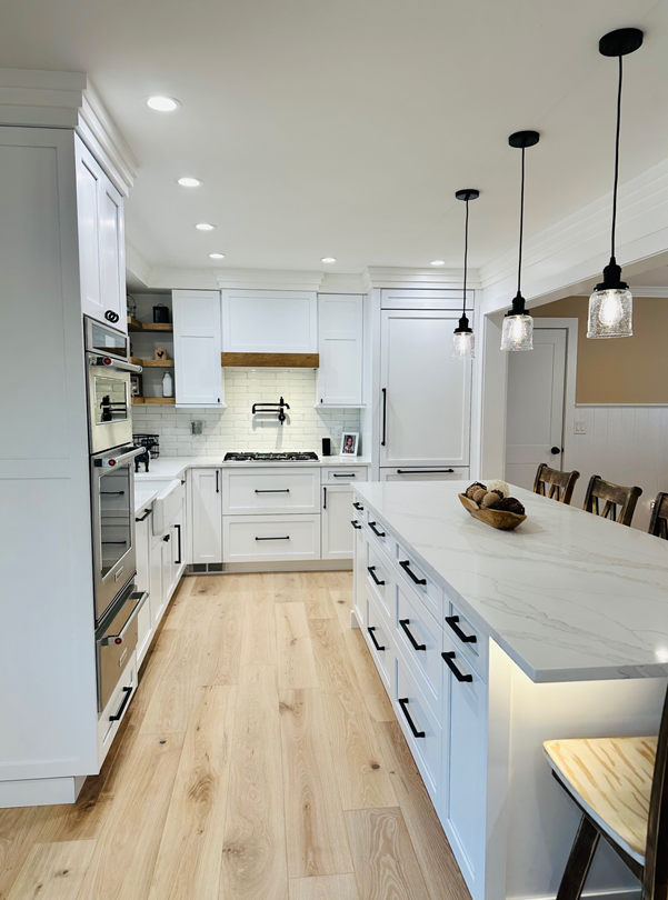 Bright white modern kitchen with island, pendant lights, and light wood flooring