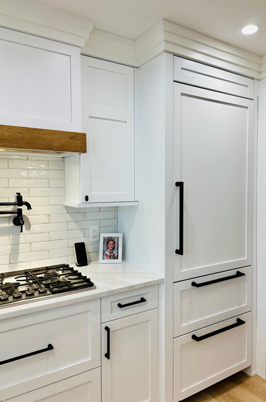 White kitchen with built-in refrigerator, gas stove, and subway tile backsplash