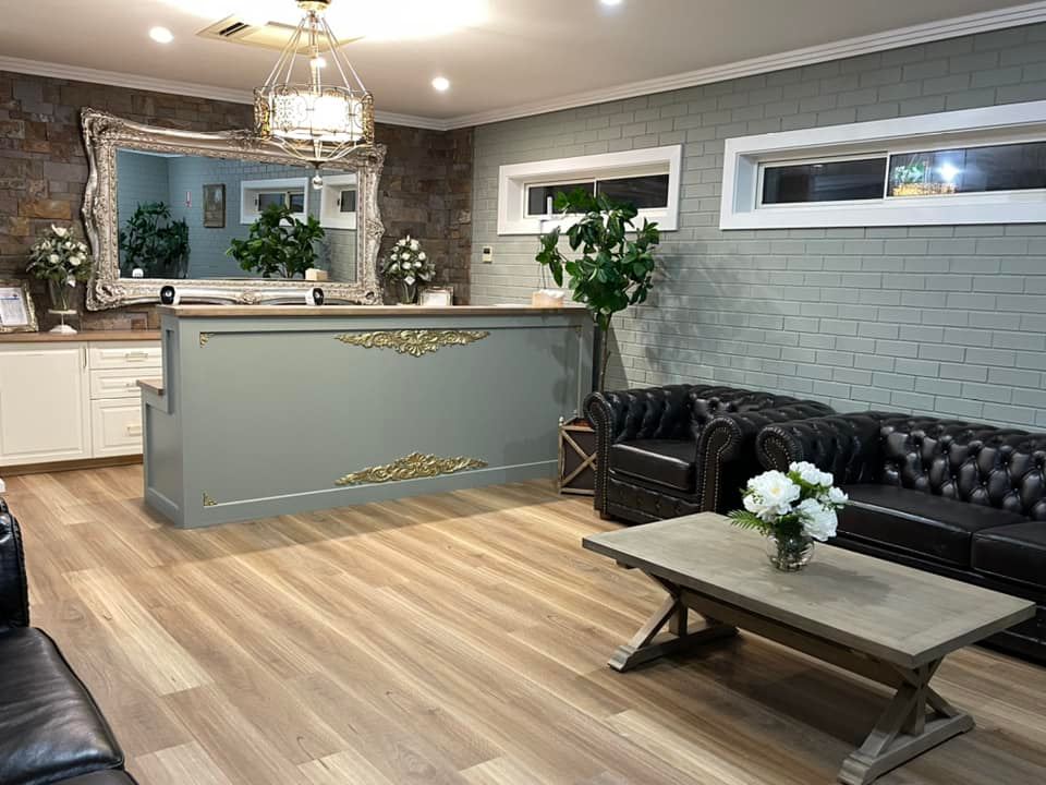 Stylish living room with tufted black sofas, coffee table, and gray accent wall behind a counter area