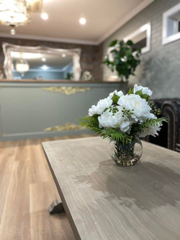 White flower arrangement on a table in a softly lit lobby or reception area.
