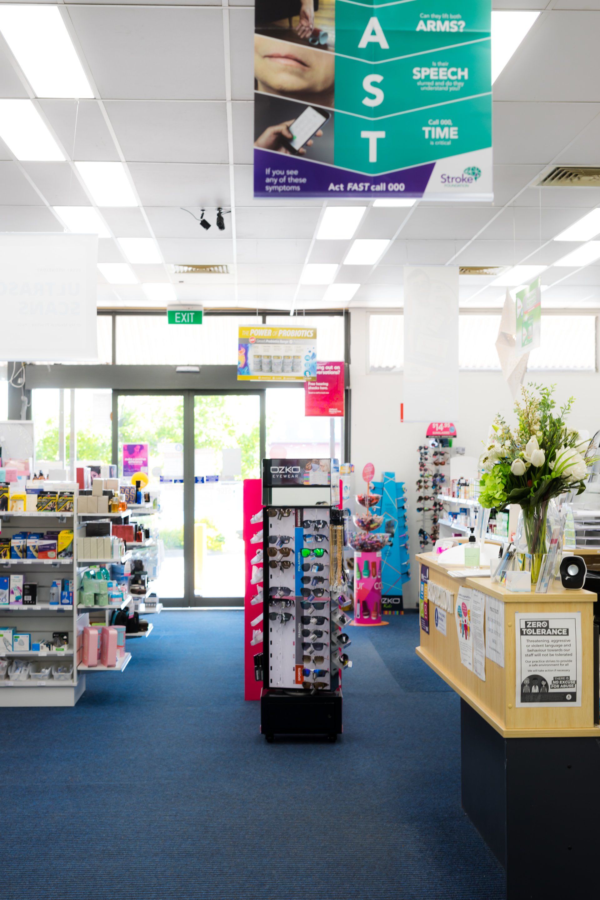 Inside a bright store entrance with shelves, blue carpet, and a hanging teal “FAST” sign