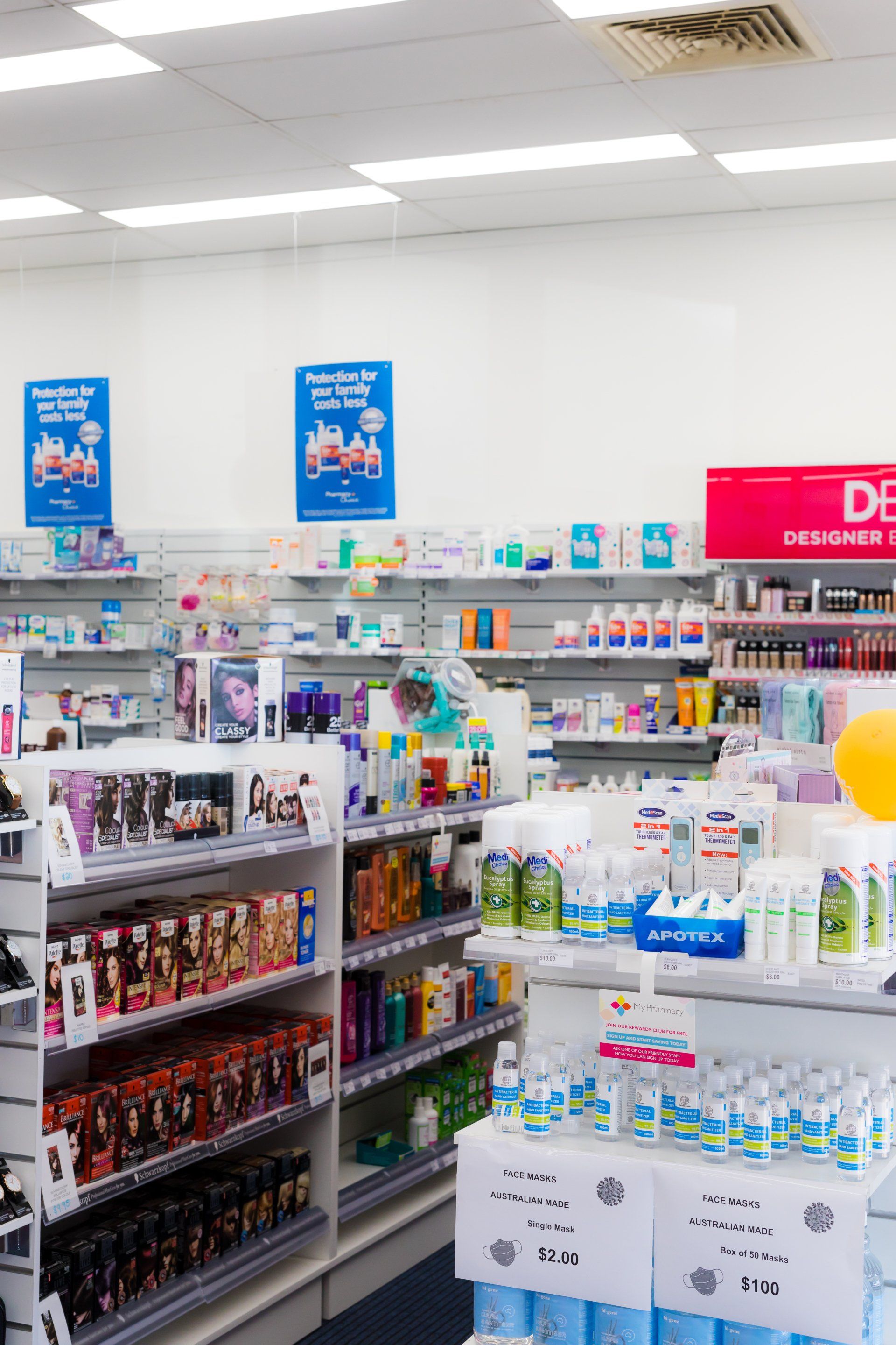 Drugstore aisle with shelves of personal care products and red sale signage under bright fluorescent lights