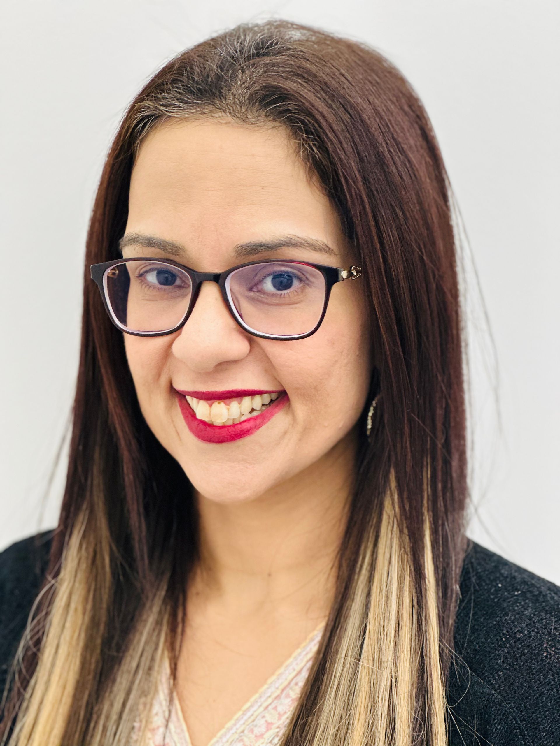 Smiling person with glasses and red lipstick against a white background