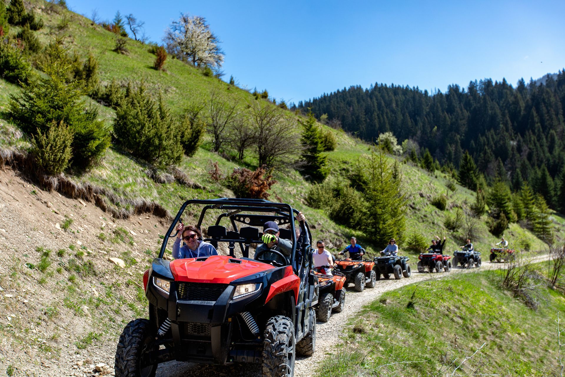 A group of people are riding atvs down a dirt road.