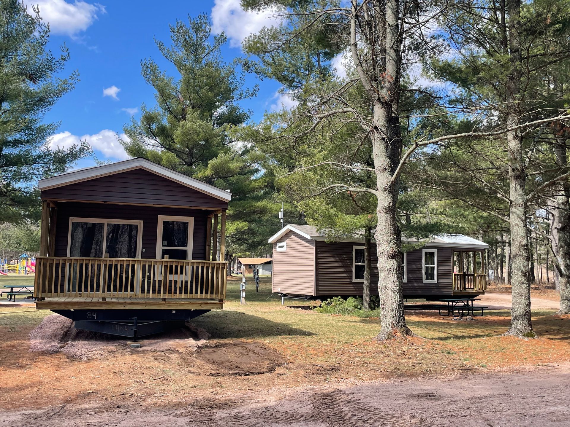 A small cabin with a deck in the middle of a forest.