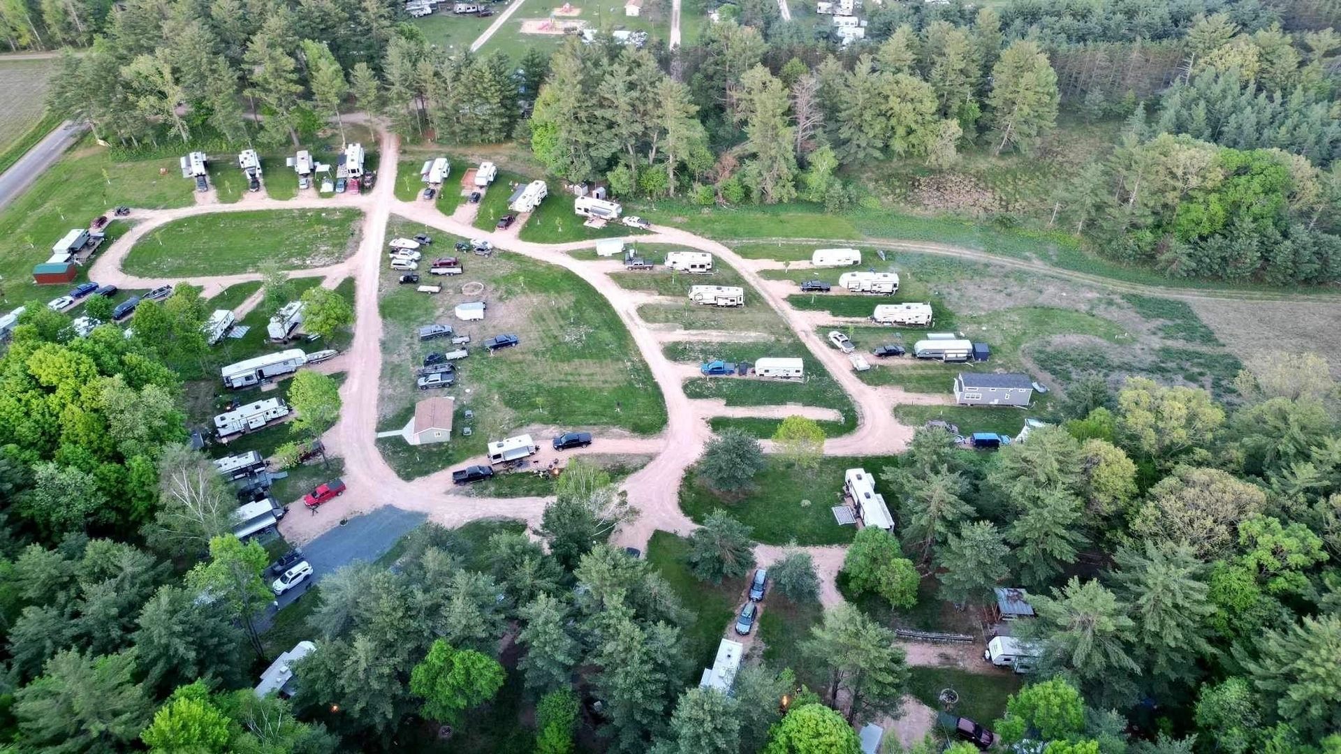 An aerial view of a campground surrounded by trees and rvs.
