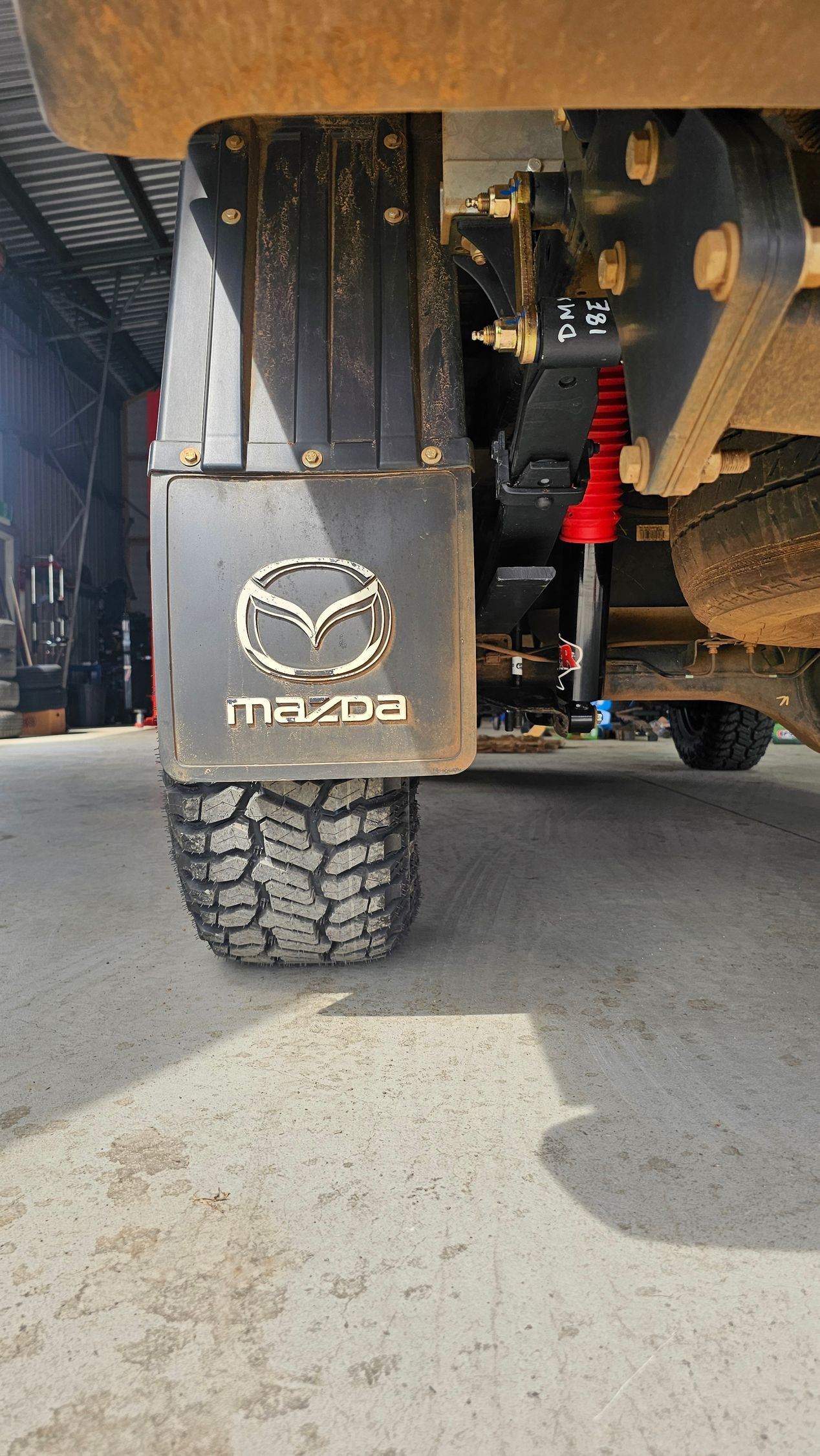 Mud Flap With Mazda Logo on Truck Tire. Red Shock Absorber Visible — Track N Back 4x4 In Mareeba, QLD