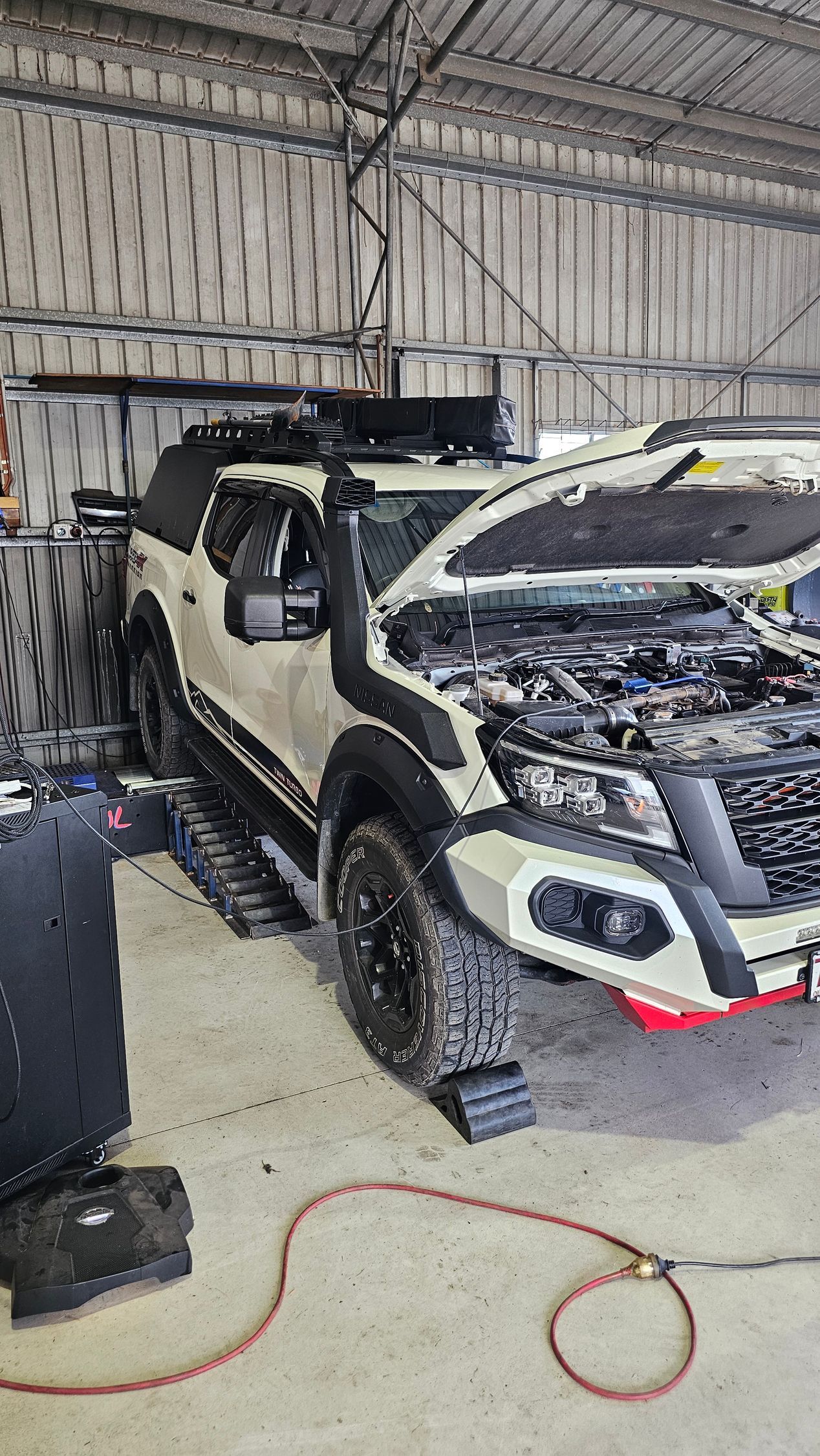 White off-road truck in a garage, hood open, with a snorkel, roof rack, and lift — Track N Back 4x4 In Mareeba, QLD