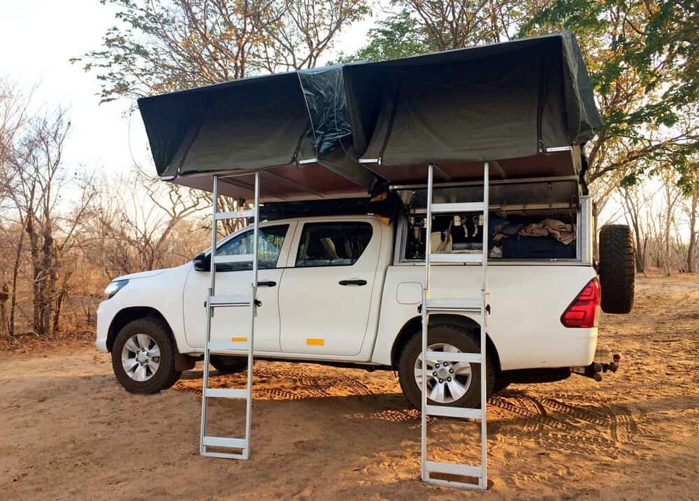 White Pickup Truck With Rooftop Tents and Ladders in a Wooded Area — Track N Back 4x4 In Townsville, QLD