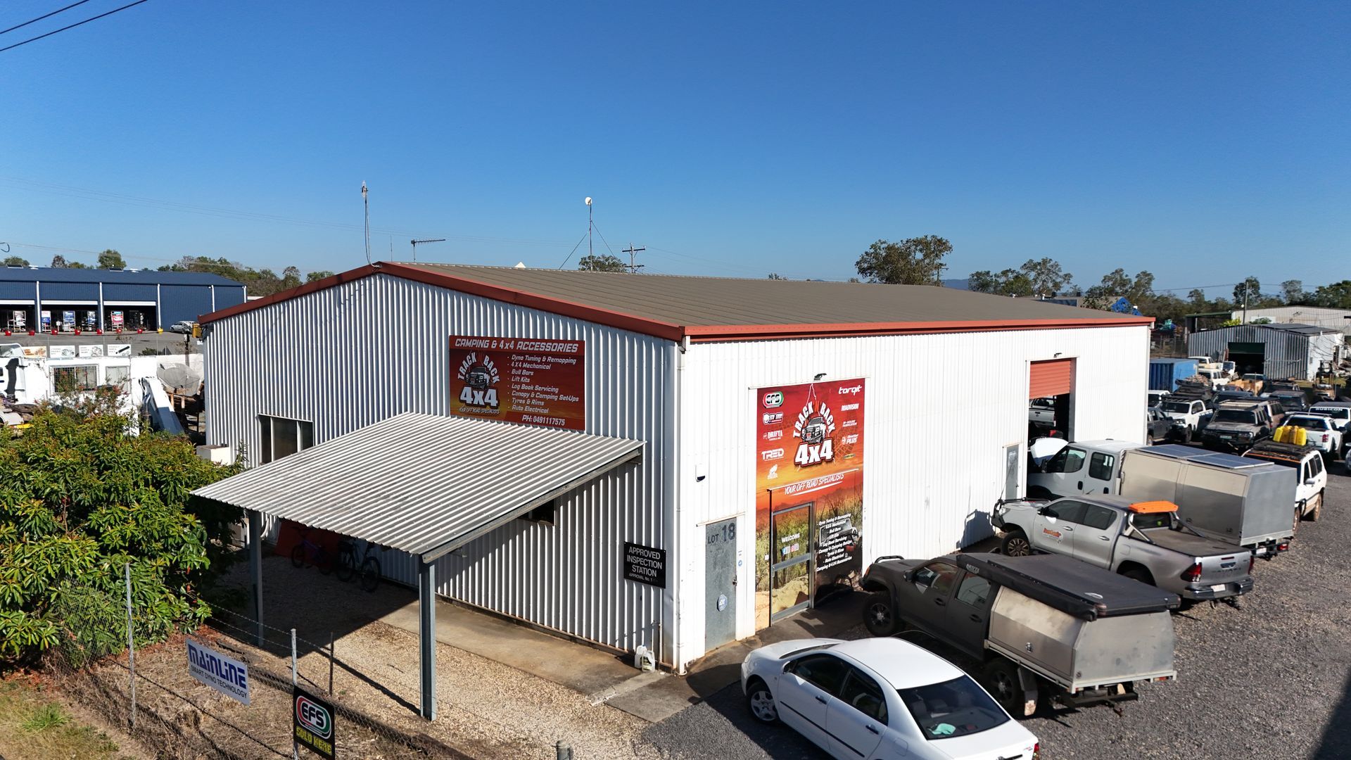 White warehouse with signage and vehicles parked outside under a blue sky — Track N Back 4x4 In Mareeba, QLD