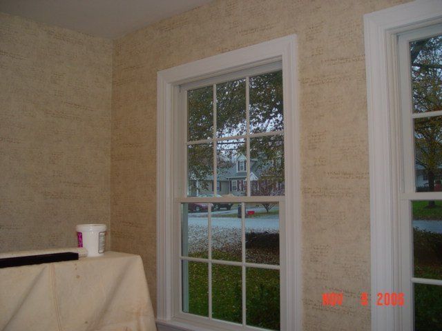 Empty beige room with two windows and a table covered in cloth, with a cup on top.