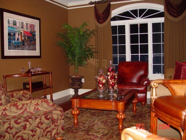 Elegant living room with red leather chair, patterned sofa, coffee table, and tall window shutters Elegant living room with red leather chair, patterned sofa, coffee table, and tall window shutters