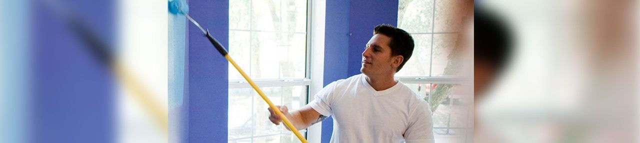 Person painting a wall with a roller in a bright room Person painting a wall with a roller in a bright room