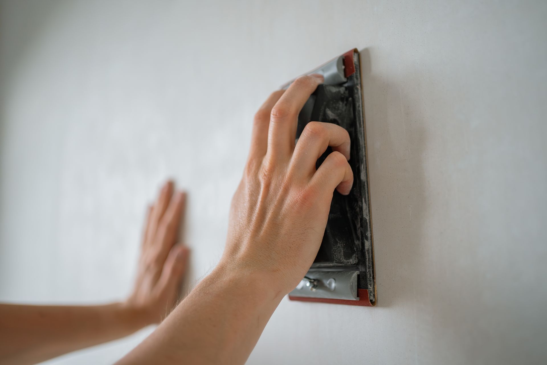 Hands installing a black electrical outlet on a white wall with a red backing plate Hands installing a black electrical outlet on a white wall with a red backing plate