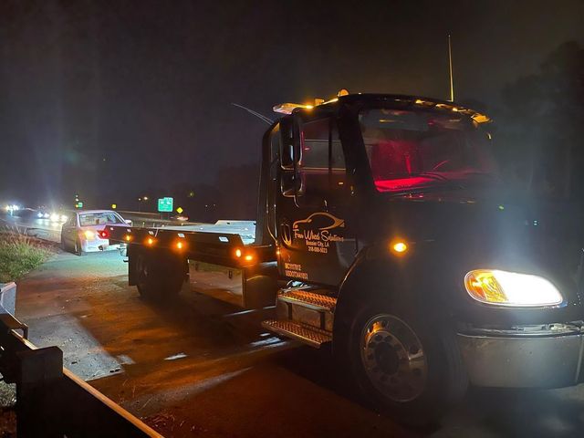 A tow truck is parked on the side of the road at night.