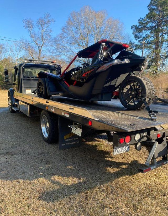 A slingshot is being towed by a tow truck.
