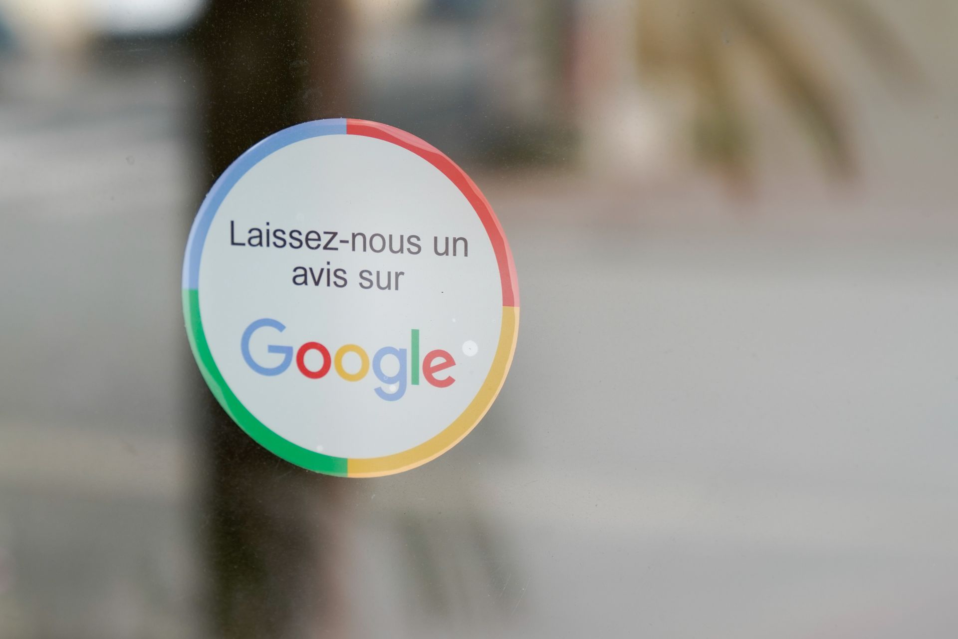 Autocollant rond Google sur verre, invitant les internautes à laisser un avis. Texte en français.