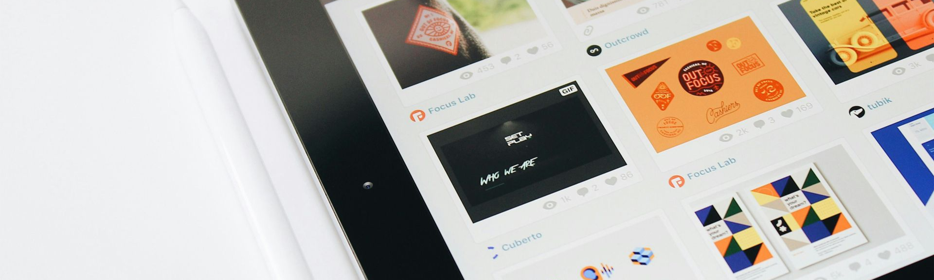 Tablette affichant une grille d'images, probablement un flux de médias sociaux, posée sur une surface blanche.