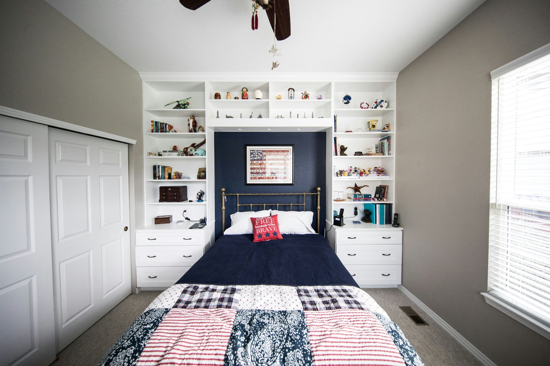 Bright bedroom with a navy accent wall, twin bed, white built-ins, and a patchwork quilt.