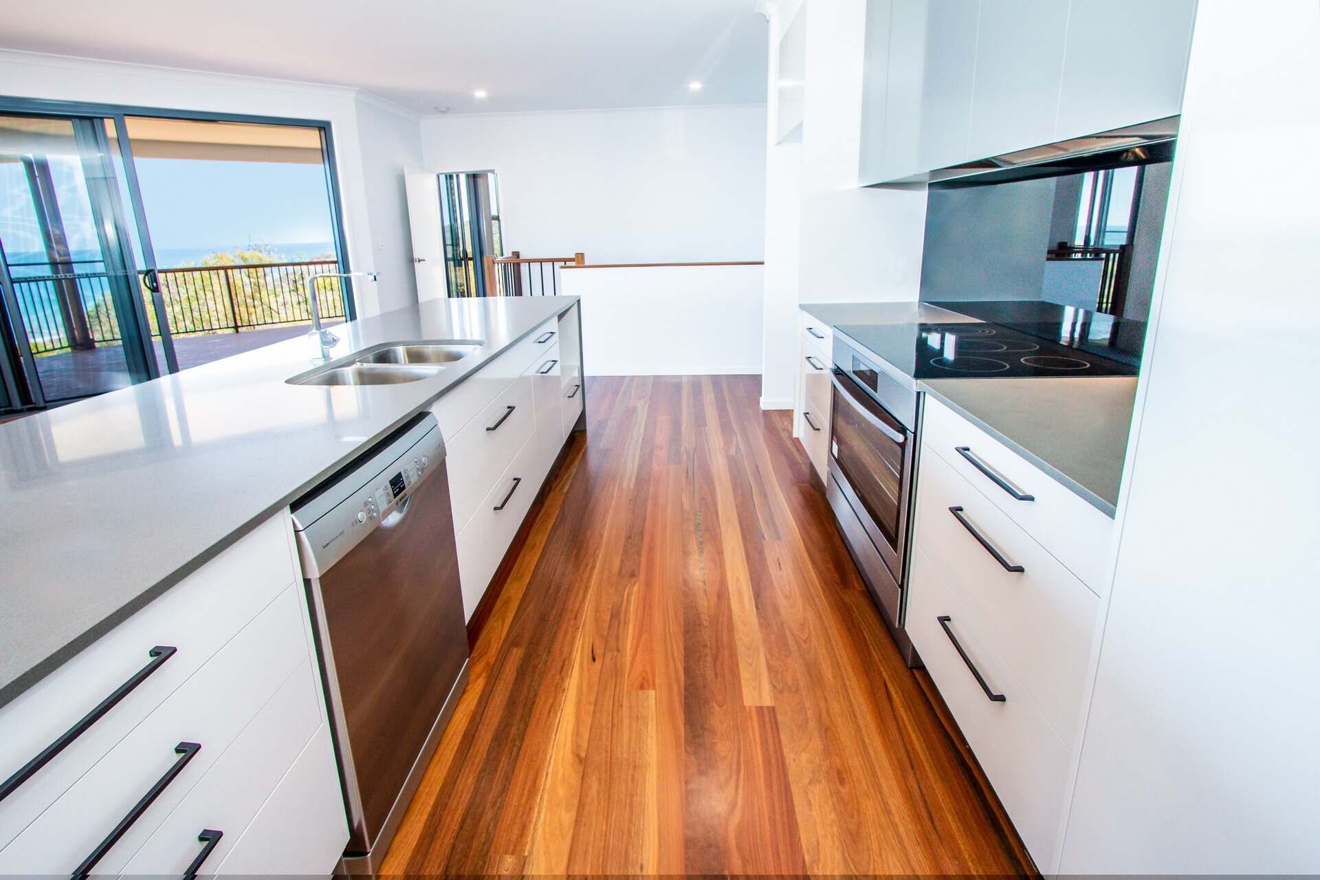 A Kitchen With Hardwood Floors and White Cabinets — Regalline Cabinets & Joinery in Svensson Heights, QLD