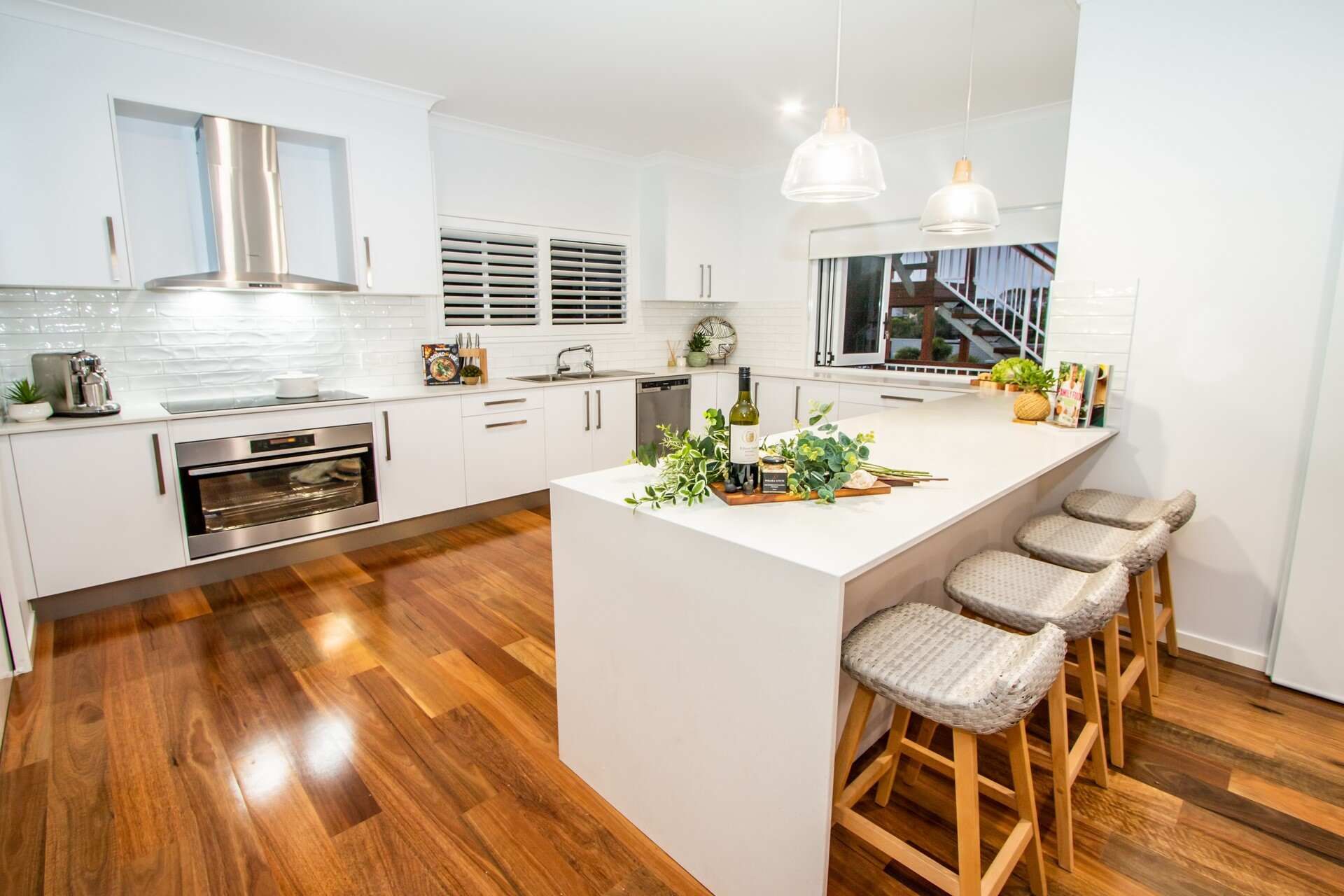 A Kitchen With Hardwood Floors, White Cabinets, Stainless Steel Appliances and a Large Island — Regalline Cabinets & Joinery in Svensson Heights, QLD