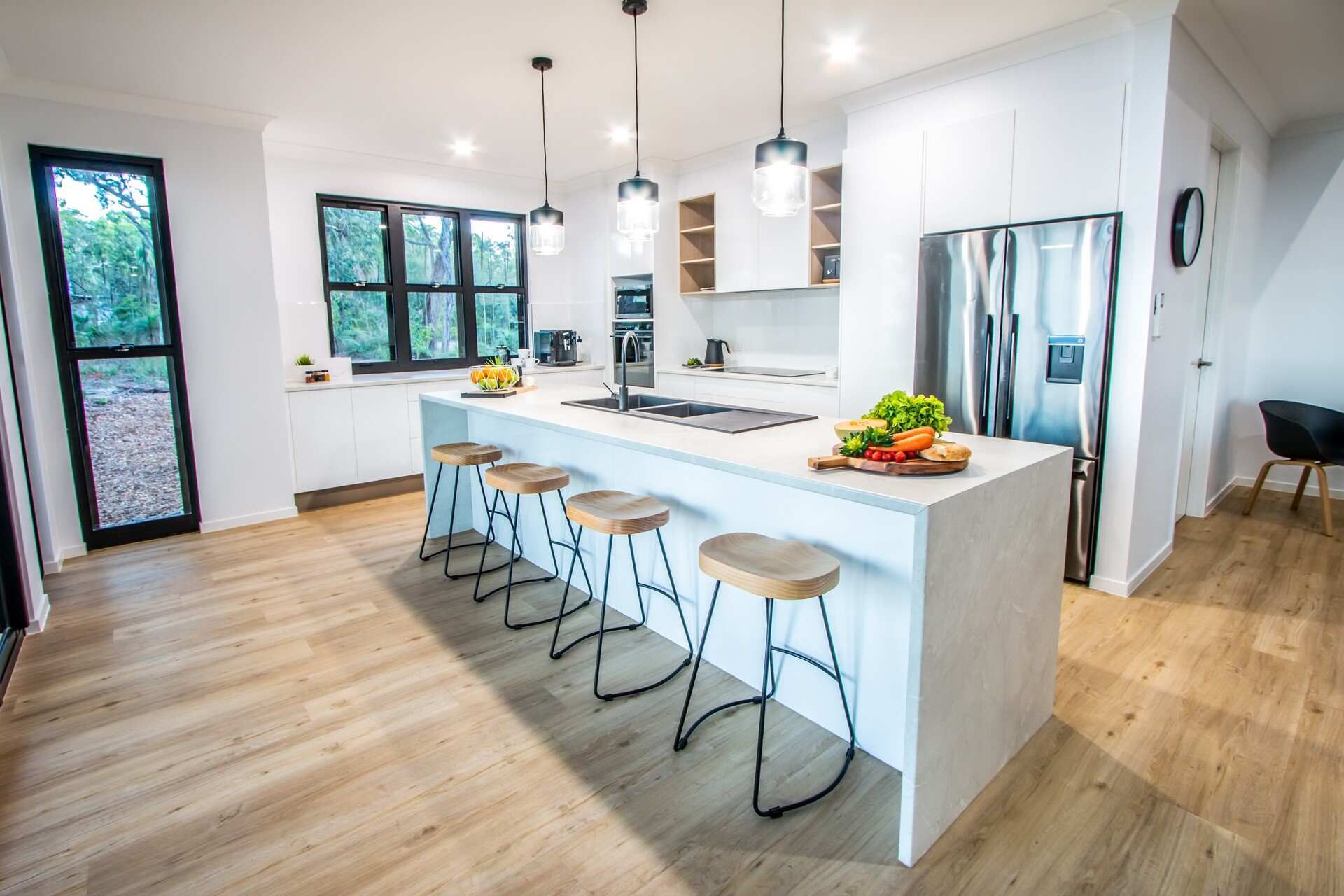 A Kitchen With a Large Island, Stools and a Refrigerator — Regalline Cabinets & Joinery in Svensson Heights, QLD