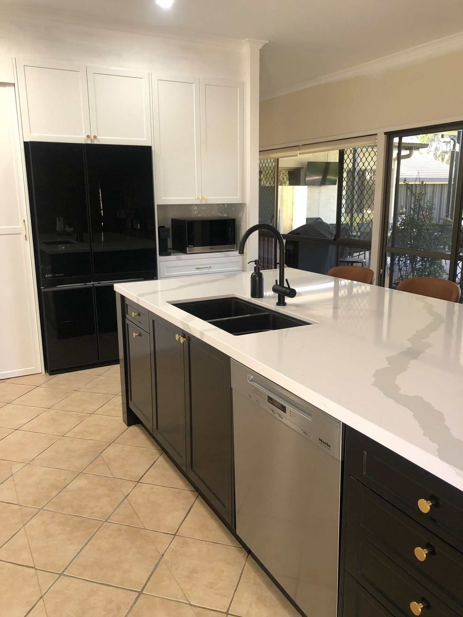 A Kitchen With Black Cabinets, Stainless Steel Appliances, a Sink and a Refrigerator — Regalline Cabinets & Joinery in Svensson Heights, QLD