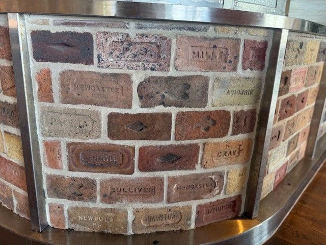 Bricklayers spreading mortar on a brick wall outdoors.