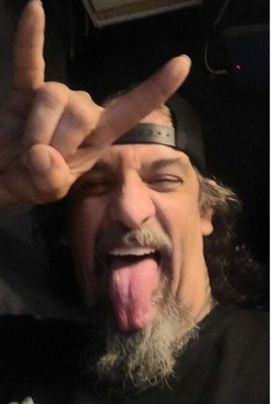 A man with a beard is sticking his tongue out